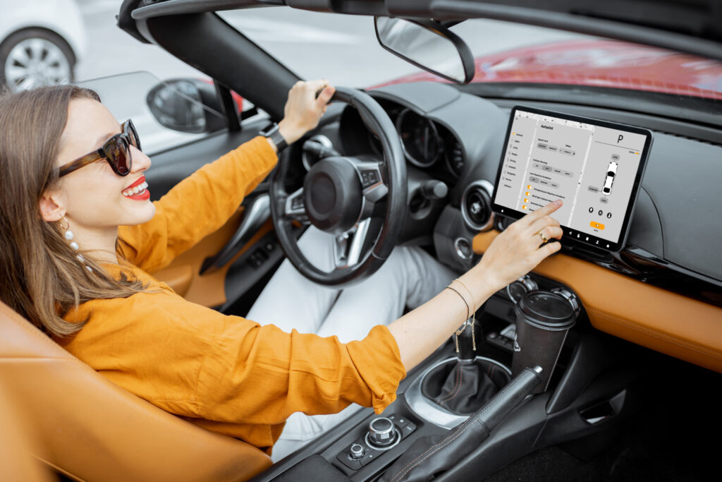 Cheerful woman controlling car with a digital dashboard, switching autopilot mode while driving a cabriolet. Smart car concept