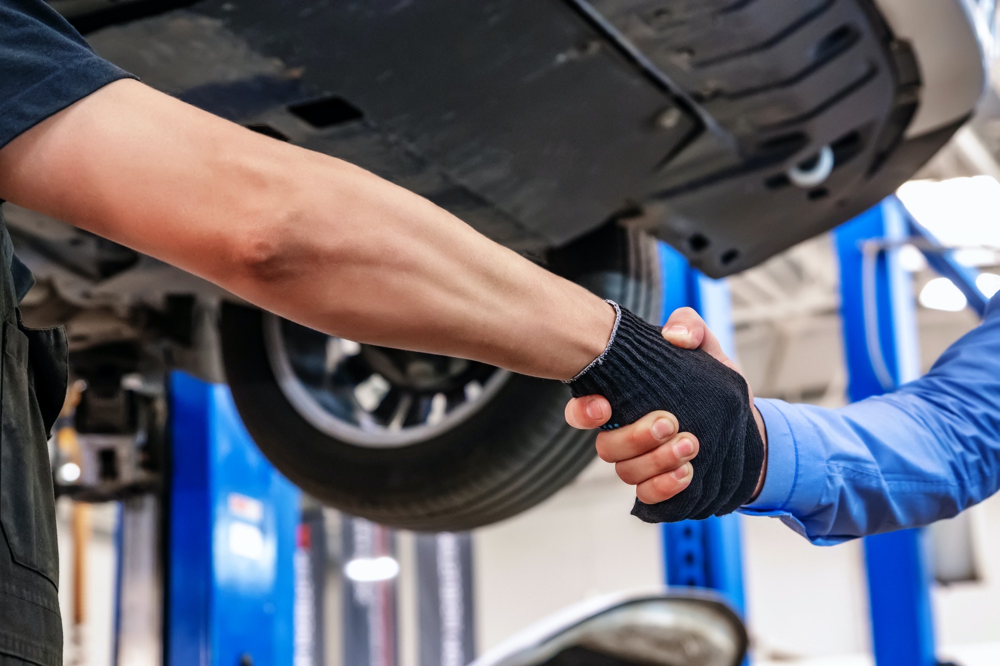 Customer and auto service mechanic shake hands. Car repair and maintenance
